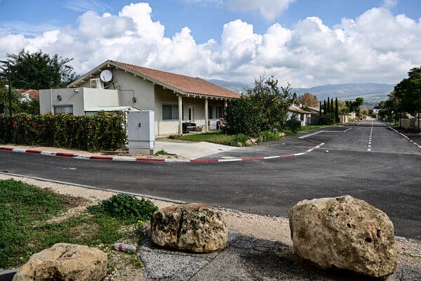 Three boulders stand across the street from a one-story house in an abandoned residential community.